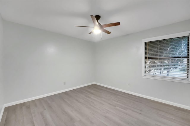 empty room with ceiling fan, baseboards, and wood finished floors