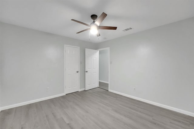 unfurnished bedroom featuring a ceiling fan, visible vents, baseboards, and wood finished floors