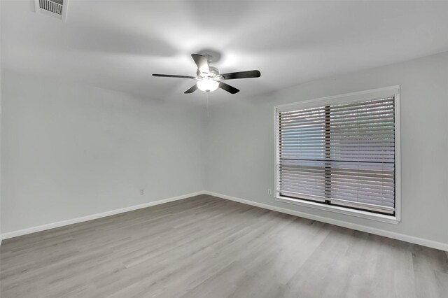 unfurnished room with a ceiling fan, wood finished floors, visible vents, and baseboards