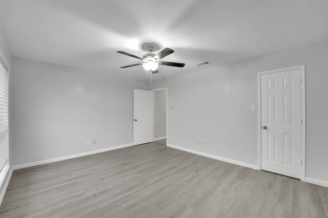 empty room with visible vents, ceiling fan, baseboards, and wood finished floors