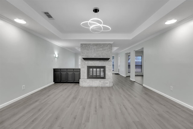 unfurnished living room with a tray ceiling, visible vents, a fireplace, and baseboards