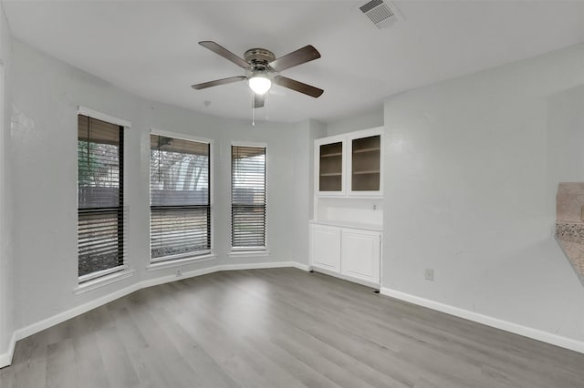 spare room with a ceiling fan, baseboards, visible vents, and wood finished floors