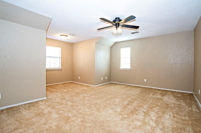 carpeted spare room featuring a textured ceiling, baseboards, visible vents, and a ceiling fan