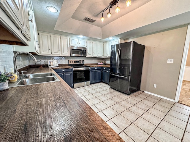 kitchen with light tile patterned floors, visible vents, appliances with stainless steel finishes, a tray ceiling, and a sink