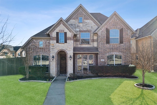 french country home with stone siding, a front lawn, and brick siding