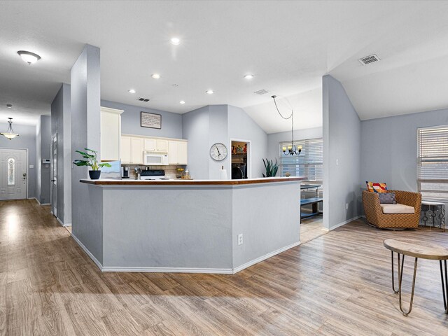 kitchen featuring visible vents, white microwave, light wood-style flooring, white cabinetry, and a notable chandelier