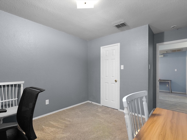 office space with carpet, a textured ceiling, visible vents, and baseboards