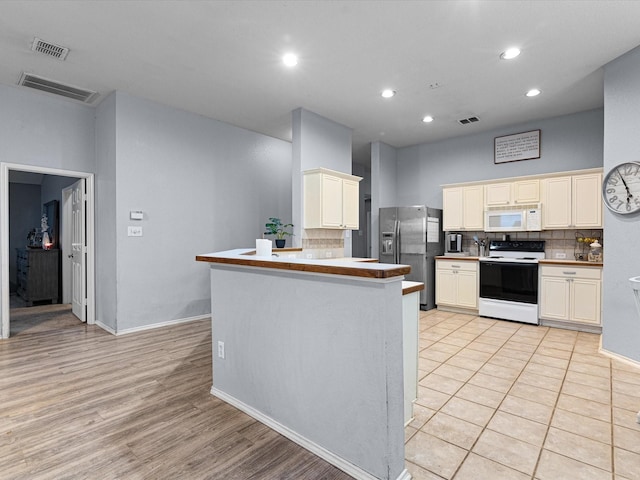 kitchen with electric range oven, white microwave, stainless steel refrigerator with ice dispenser, and visible vents