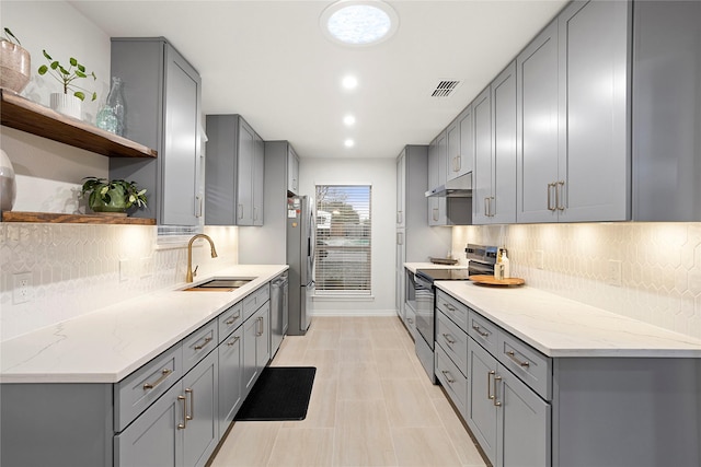 kitchen featuring open shelves, gray cabinetry, appliances with stainless steel finishes, a sink, and under cabinet range hood