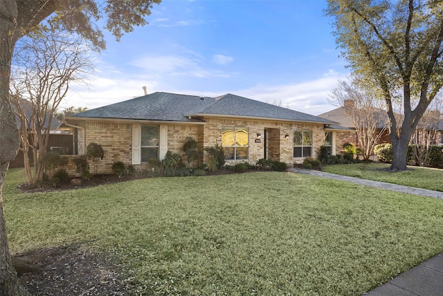 single story home featuring a front yard, brick siding, and roof with shingles