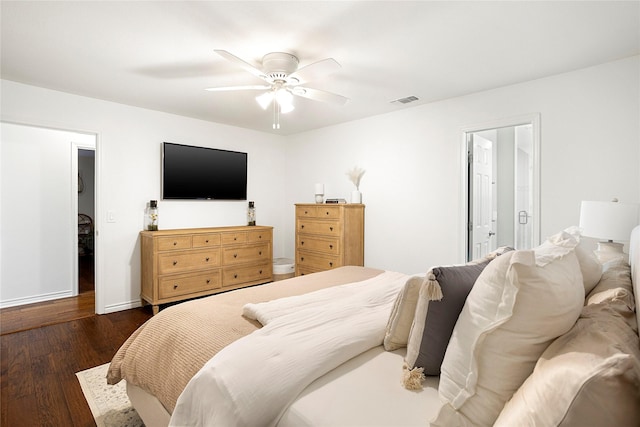 bedroom featuring a ceiling fan, dark wood-style flooring, visible vents, and baseboards