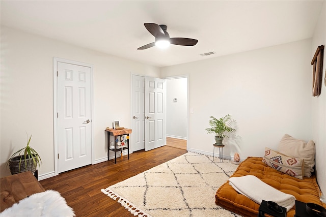 living area with a ceiling fan, visible vents, baseboards, and wood finished floors