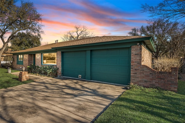 single story home with a garage, concrete driveway, brick siding, and a lawn