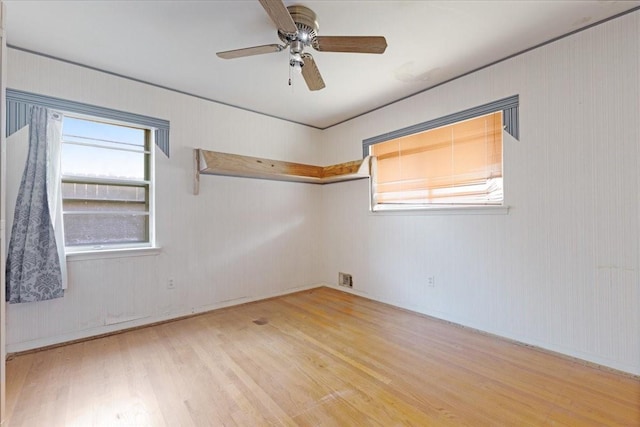 spare room with a ceiling fan, visible vents, and wood finished floors