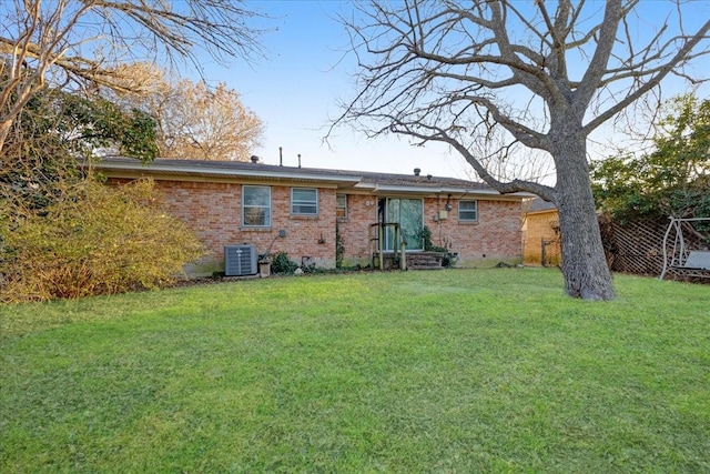 rear view of property with brick siding, a lawn, and central AC unit