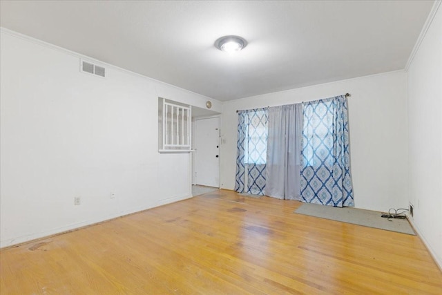 unfurnished room with visible vents, ornamental molding, and wood finished floors