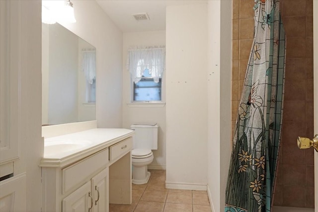 bathroom featuring toilet, vanity, tile patterned flooring, tiled shower, and baseboards