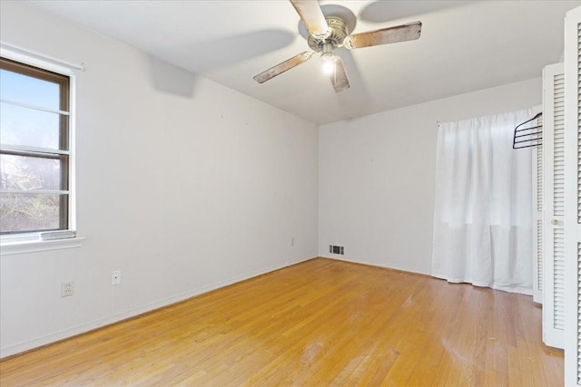 empty room with baseboards, visible vents, a ceiling fan, and light wood-style floors