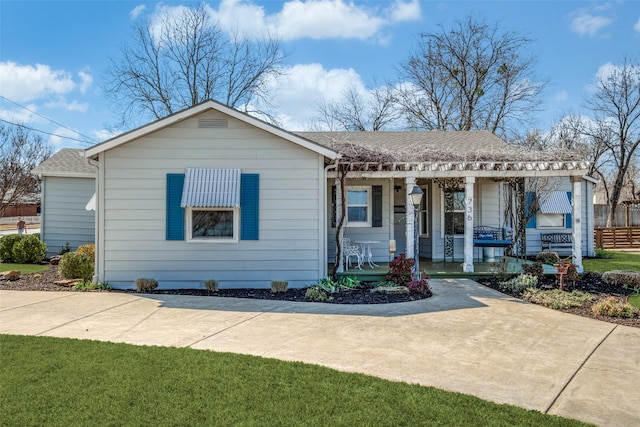 view of front of home featuring covered porch, roof with shingles, and fence