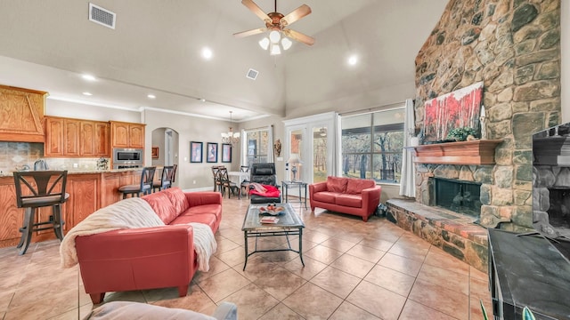 living room featuring light tile patterned floors, ceiling fan with notable chandelier, a fireplace, and visible vents