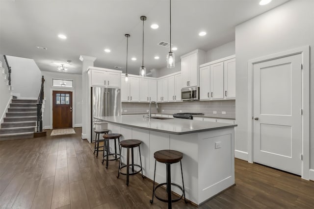 kitchen with stainless steel appliances, white cabinets, dark wood-type flooring, and a sink