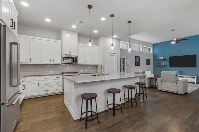 kitchen with visible vents, open floor plan, dark wood-style flooring, stainless steel appliances, and a sink