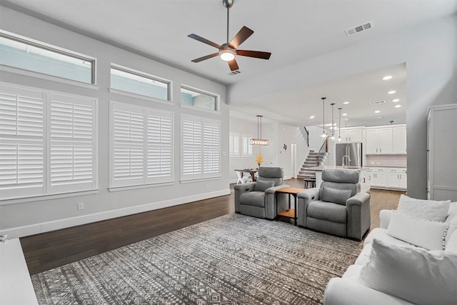 living room featuring visible vents, stairway, ceiling fan, wood finished floors, and baseboards