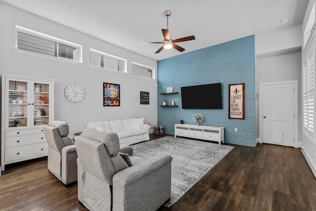 living room featuring ceiling fan, an accent wall, and wood finished floors