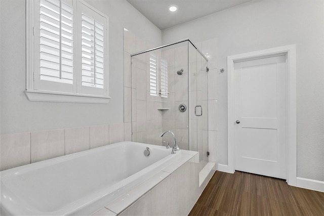 bathroom featuring tiled bath, baseboards, and a shower stall