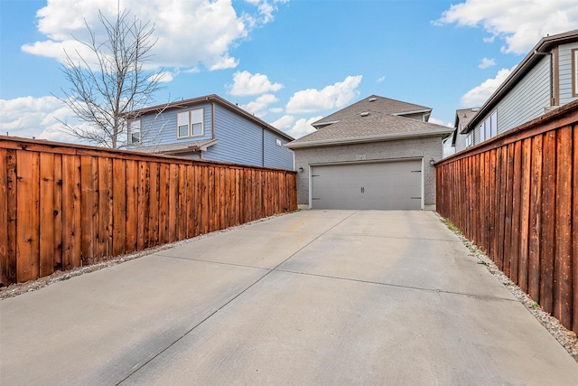 view of side of property with a garage, fence, and roof with shingles