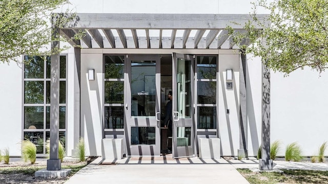 entrance to property featuring a pergola and stucco siding