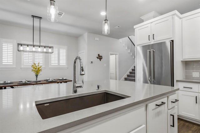 kitchen featuring tasteful backsplash, a sink, hanging light fixtures, and high end refrigerator