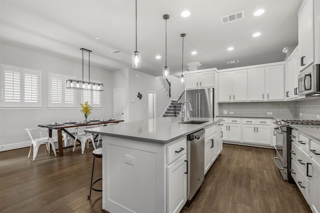 kitchen featuring dark wood-style floors, visible vents, appliances with stainless steel finishes, and decorative backsplash