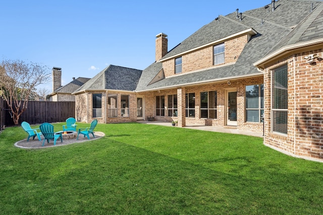 rear view of property with a patio, an outdoor fire pit, brick siding, fence, and a yard