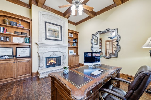 office area with dark wood finished floors, a ceiling fan, ornamental molding, beamed ceiling, and a fireplace