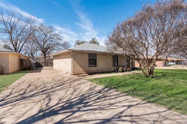 view of front facade featuring brick siding, concrete driveway, roof with shingles, fence, and a front yard