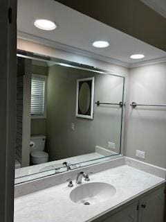 bathroom with toilet, recessed lighting, crown molding, and vanity