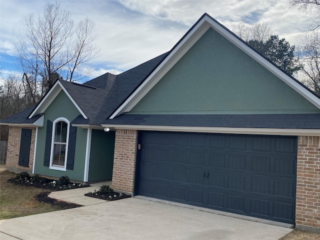 single story home featuring brick siding, stucco siding, a shingled roof, an attached garage, and driveway