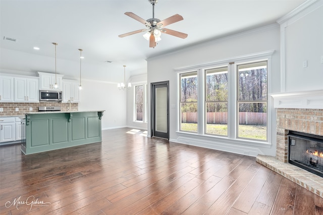 unfurnished living room featuring dark wood-style floors, a fireplace, baseboards, and ornamental molding