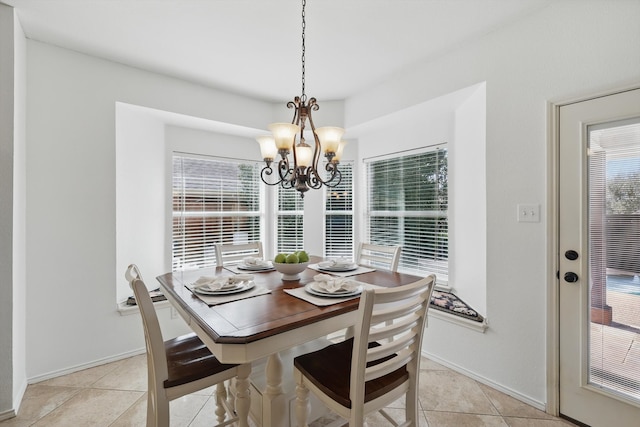 dining space with a healthy amount of sunlight, an inviting chandelier, light tile patterned floors, and baseboards