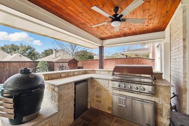 view of patio featuring exterior kitchen, a fenced backyard, an outdoor structure, and grilling area