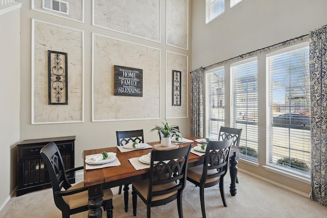 dining room featuring baseboards, a healthy amount of sunlight, visible vents, and light colored carpet