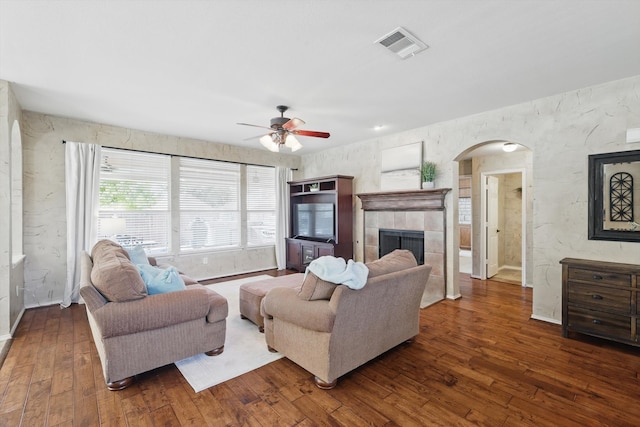 living room featuring arched walkways, visible vents, a fireplace, and hardwood / wood-style flooring