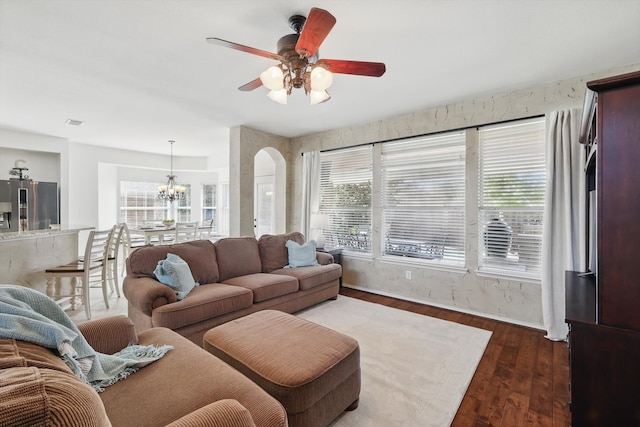 living area featuring a healthy amount of sunlight, arched walkways, wood finished floors, and ceiling fan with notable chandelier