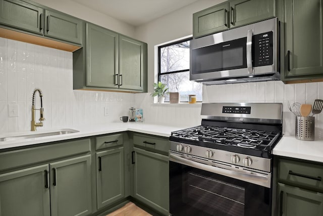 kitchen with stainless steel appliances, a sink, and green cabinetry