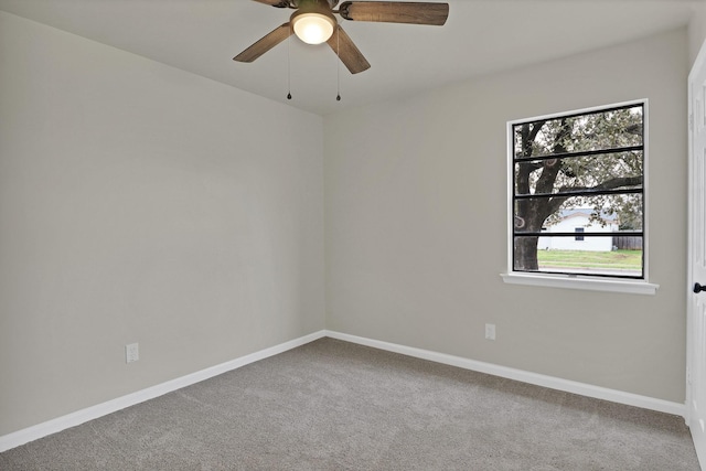 carpeted spare room featuring baseboards and a ceiling fan