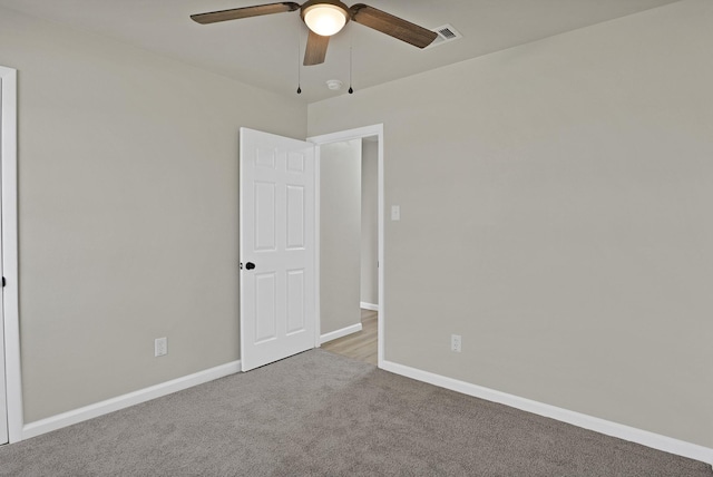 carpeted empty room featuring a ceiling fan, visible vents, and baseboards