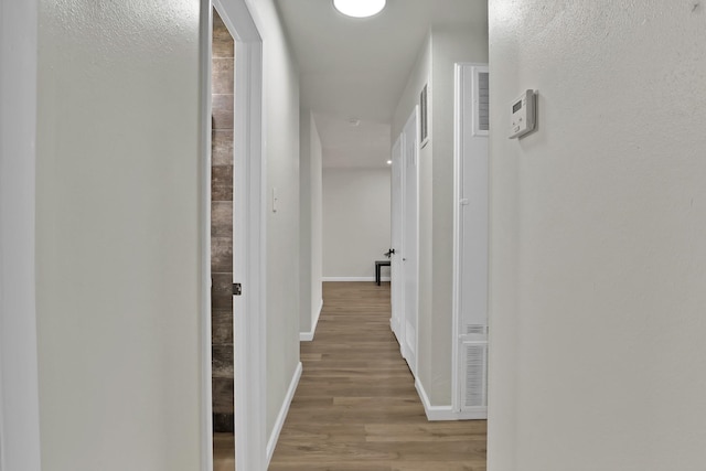 corridor featuring baseboards and wood finished floors