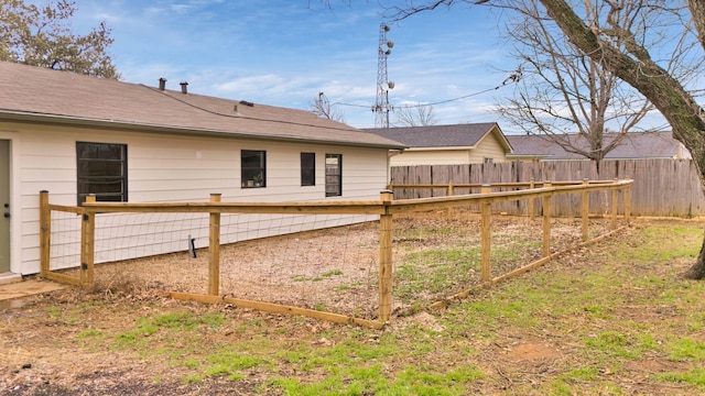 rear view of house with a shingled roof and fence