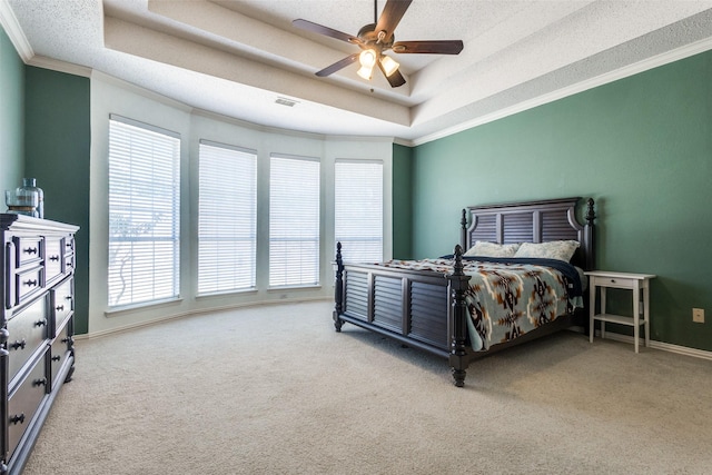 bedroom featuring visible vents, a ceiling fan, ornamental molding, carpet, and a tray ceiling